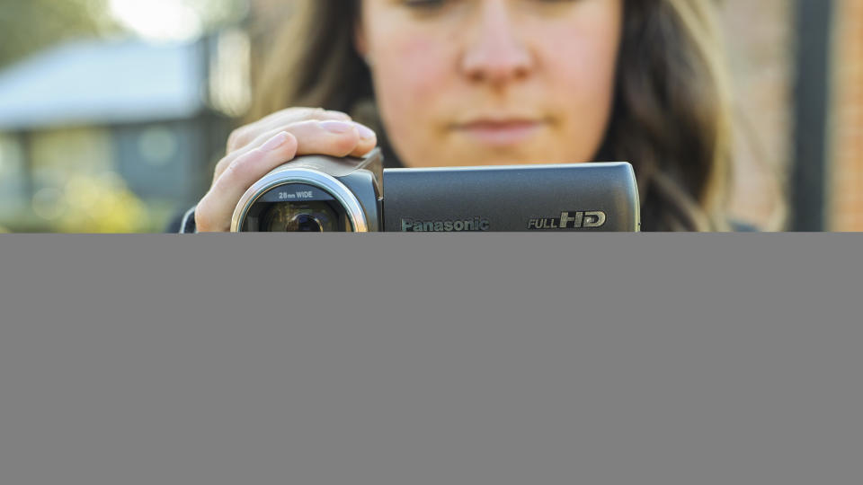 The Panasonic HC-V180 camcorder being held by a young woman