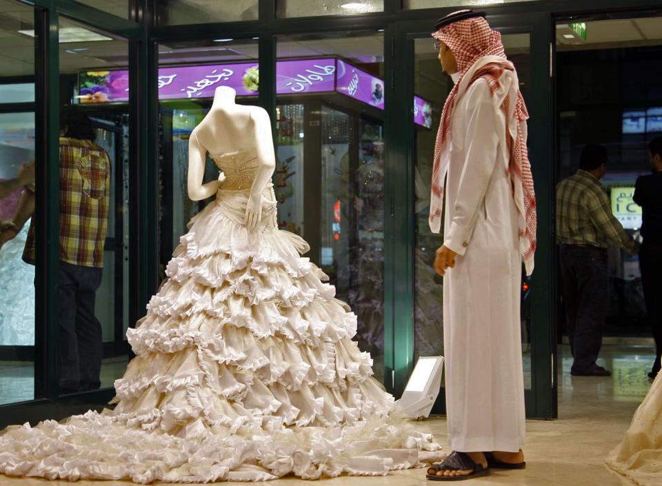 FILE - In this Sunday, Aug. 3, 2008 file photo, a Saudi man stands in front of a wedding dress at a shop in Riyadh, Saudi Arabia. In the Middle East, Saudi Arabia and Yemen are the only Arab countries that do not have laws that set a minimum age for marriage. According to a December 2011 Human Rights Watch report, approximately 14 percent of girls in the Arab world’s poorest nation of Yemen were married before the age 15, and 52 percent were married before 18 years old. (AP Photo, File)