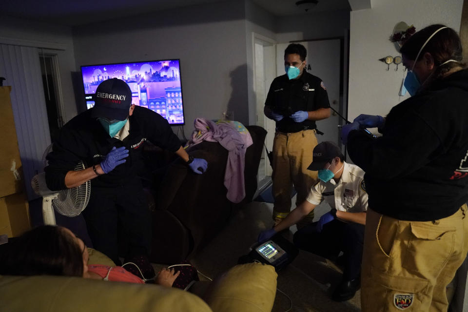 A patient is surrounded by emergency medical workers Joshua Hammond, from left, Trenton Amaro, Thomas Hoang and Kim Rose while being treated in her apartment in Placentia, Calif., Saturday, Jan. 9, 2021. EMTs and paramedics have always dealt with life and death — they make split-second decisions about patient care, which hospital to race to, the best and fastest way to save someone — and now they're just a breath away from becoming the patient themselves. (AP Photo/Jae C. Hong)