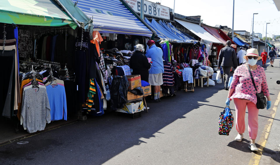 Customers stroll through Shepherd's bush market that is allowed to reopen after the COVID-19 lockdown in London, Monday, June 1, 2020. The British government has lifted some lockdown restrictions to restart social life and activate the economy while still endeavouring to limit the spread of the highly contagious COVID-19 coronavirus.(AP Photo/Frank Augstein)