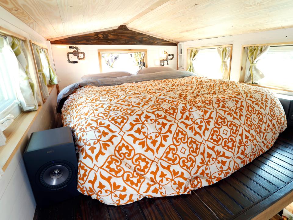 The lofted bedroom with an orange comforter on the bed inside Alexis Stephens' tiny house