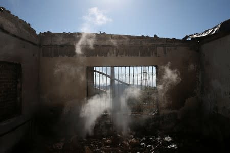Smoke rises inside a burned house during a wildfire on Mount Hymettus, near Athens
