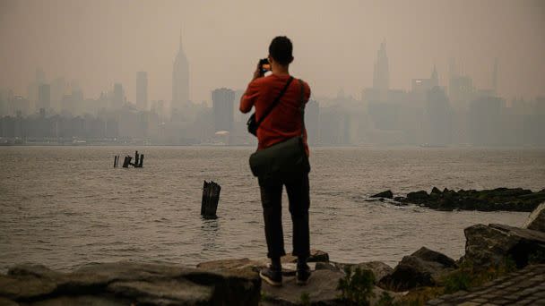 PHOTO: A man stands before the New York city skyline and east river shrouded in smoke, in Brooklyn, June 6, 2023. (Ed Jones/AFP via Getty Images)