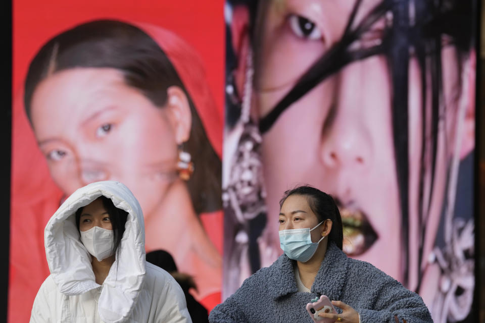 Women wearing masks walk past ads featuring models for make up products in Beijing, China, Tuesday, Dec. 28, 2021. Advertisements featuring some Chinese models have sparked feuding in China over whether their appearance and makeup are perpetuating harmful stereotypes of Asians. (AP Photo/Ng Han Guan)