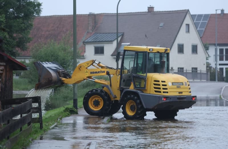 Helpers try to free a road on the Mindel from flooding with an excavator.  Karl-Josef Hildenbrand/dpa