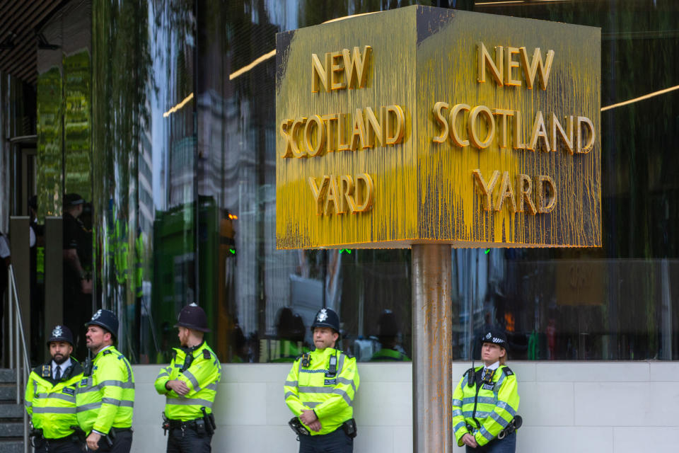 Metropolitan Police officers monitor a revolving sign outside New Scotland Yard which had been spray painted by a climate activist from Just Stop Oil to call on the UK government to cease issuing oil and gas licences on 14 October 2022 in London, United Kingdom. Some activists also used glue and lock-on tubes to block the road in front of New Scotland Yard. The Metropolitan Police made 24 arrests on suspicion of wilful obstruction of the highway and/or conspiracy to commit criminal damage. (photo by Mark Kerrison/In Pictures via Getty Images)