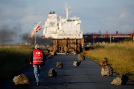 A French CGT labour union employee walks near a barricade to block the entrance of the fuel depot of the society SFDM near the oil refinery of Donges, France, May 23, 2016. REUTERS/Stephane Mahe