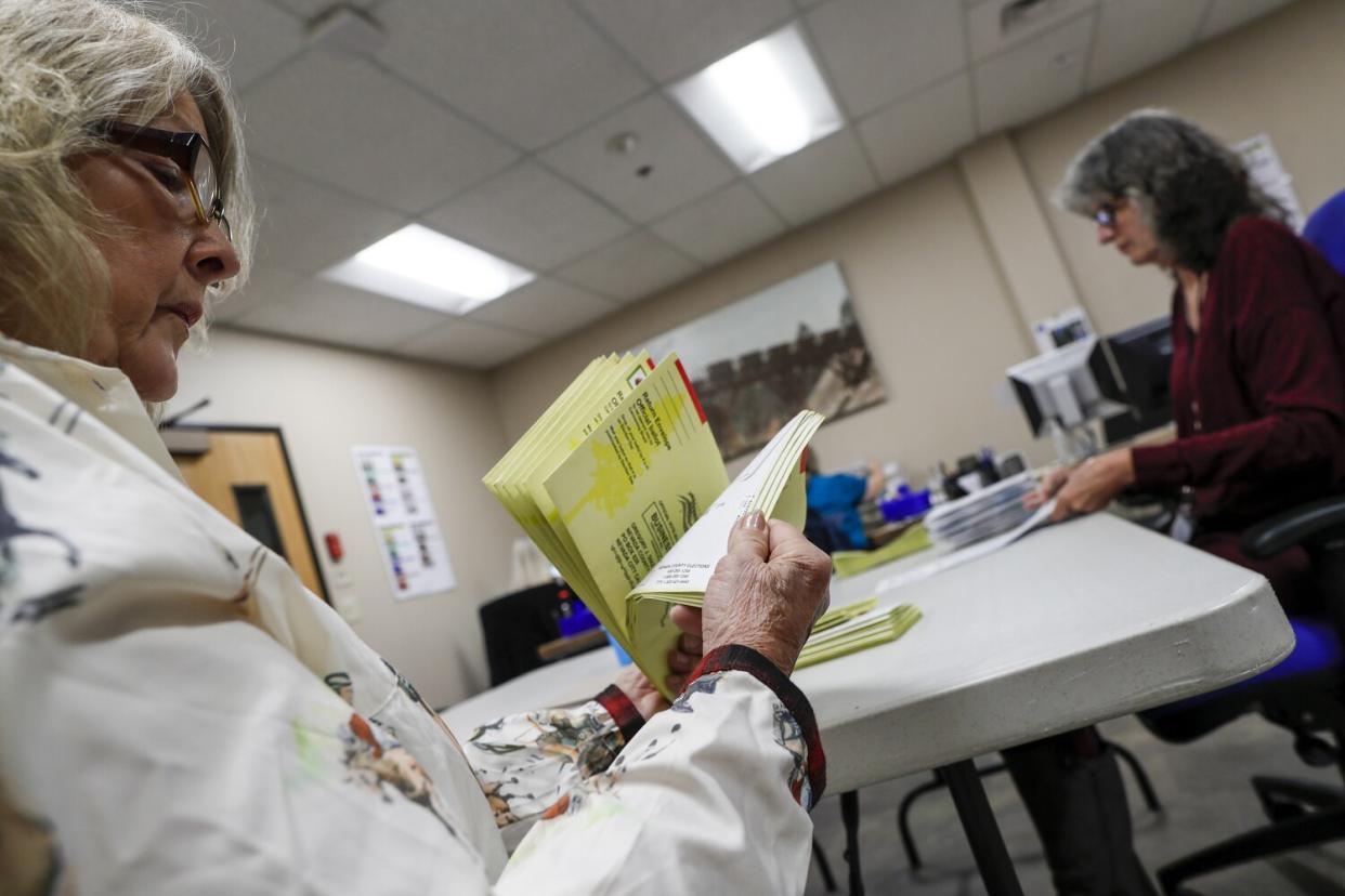 A worker flips through envelopes at a table in an office