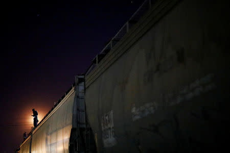 A Central American migrant, moving in a caravan through Mexico, stands on a wagon of a freight train as he embarks on a new leg of their travels, in Tlaquepaque, in Jalisco state, Mexico April 19, 2018. REUTERS/Edgard Garrido