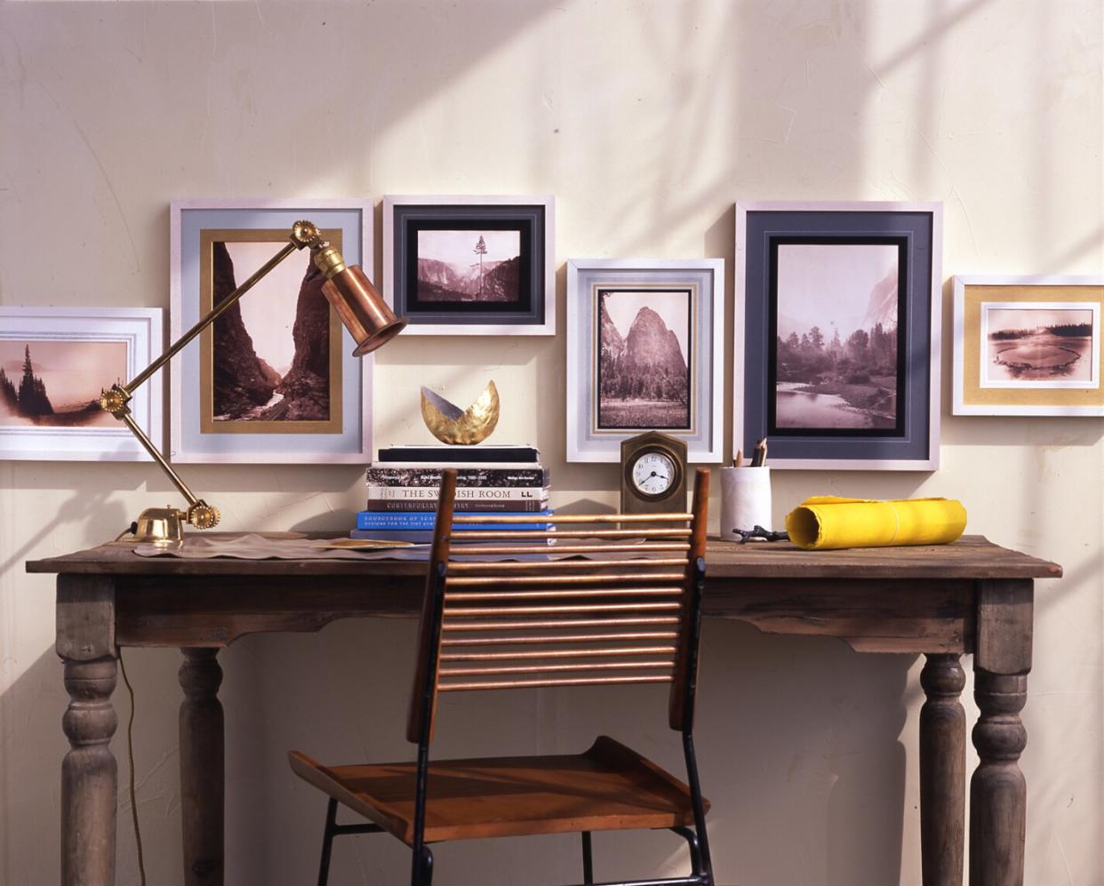 framed landscape photography hanging above writing desk