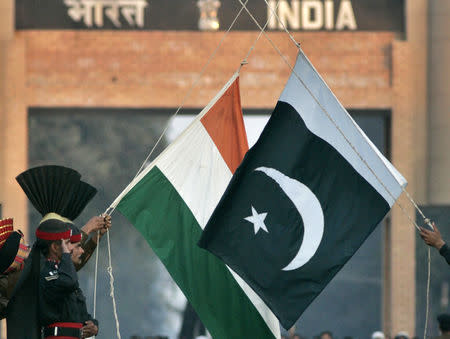 Pakistani Rangers and Indian Border Security Force personnel (obscured) lower the flags of the two countries during a daily flag lowering ceremony at the India-Pakistan joint border at Wagah some 20 km (12 miles) to the east of Lahore, December 14, 2006. REUTERS/Mian Khursheed/File Photo