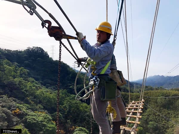 台電員工在數十公尺高的空中進行緊線作業工程。