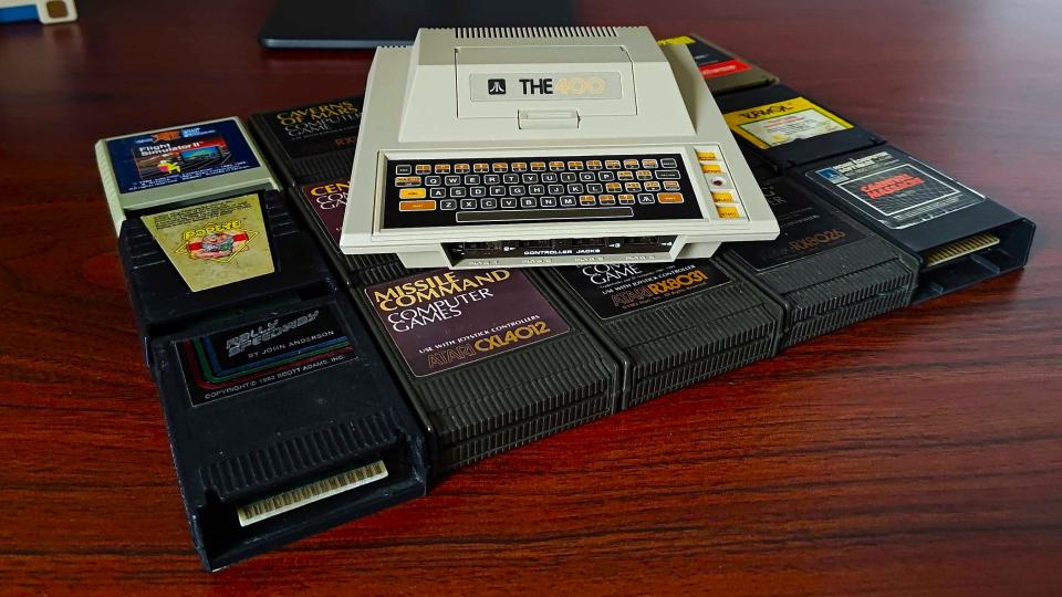 THE400 Mini console sitting on cartridges on woodgrain desk