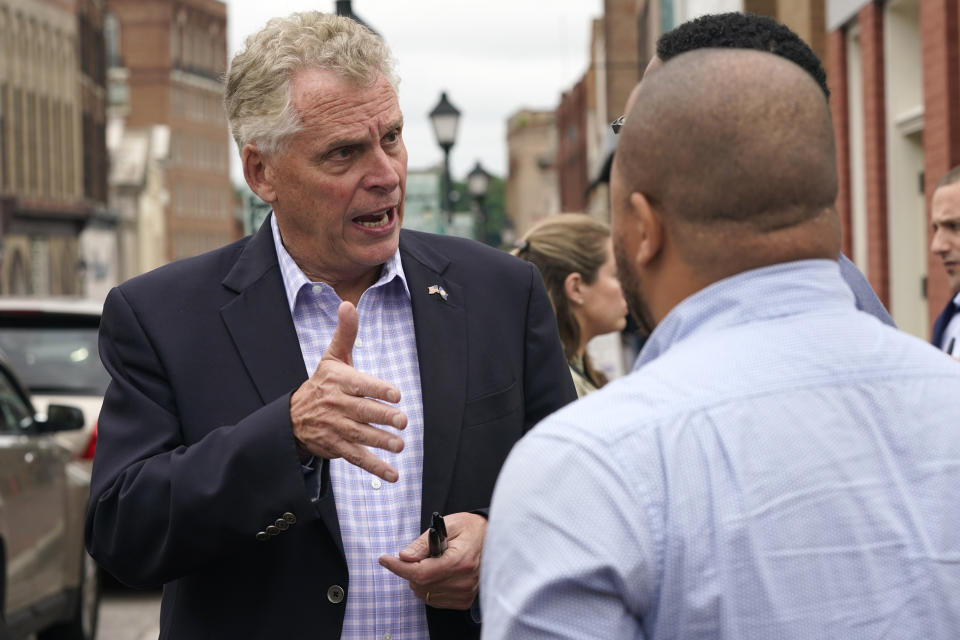 Democratic gubernatorial candidate, former Gov. Terry McAuliffe, left, talks with supporters during a tour of downtown Petersburg, Va., Saturday, May 29, 2021. McAuliffe faces four other Democrats in the a primary June 8. (AP Photo/Steve Helber)