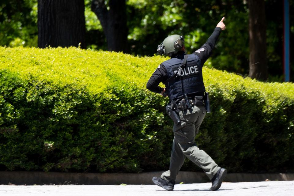 A police officer runs while pointing to a roof after a shooting in Atlanta on Wednesday, May 3, 2023. 4