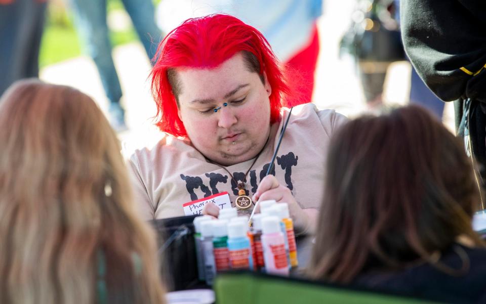 Phoenix Rayng works on art during the "End hate, elevate and celebrate trans joy" demonstration at the Monroe County Courthouse on Sunday, April 2, 2023.