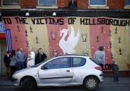 Fans stand by a flag before a memorial service to mark the 25th anniversary of the Hillsborough disaster at Anfield in Liverpool, northern England April 15, 2014. REUTERS/Darren Staples