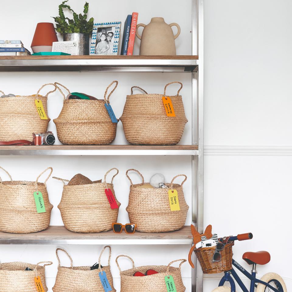 Open shelving with labelled storage baskets and a child's bike leaned against it