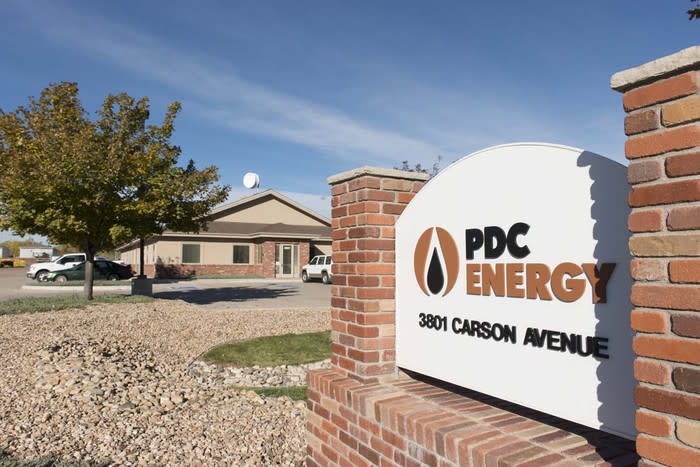 Sign reading PDC Energy in front of a small office building and rock landscaping.