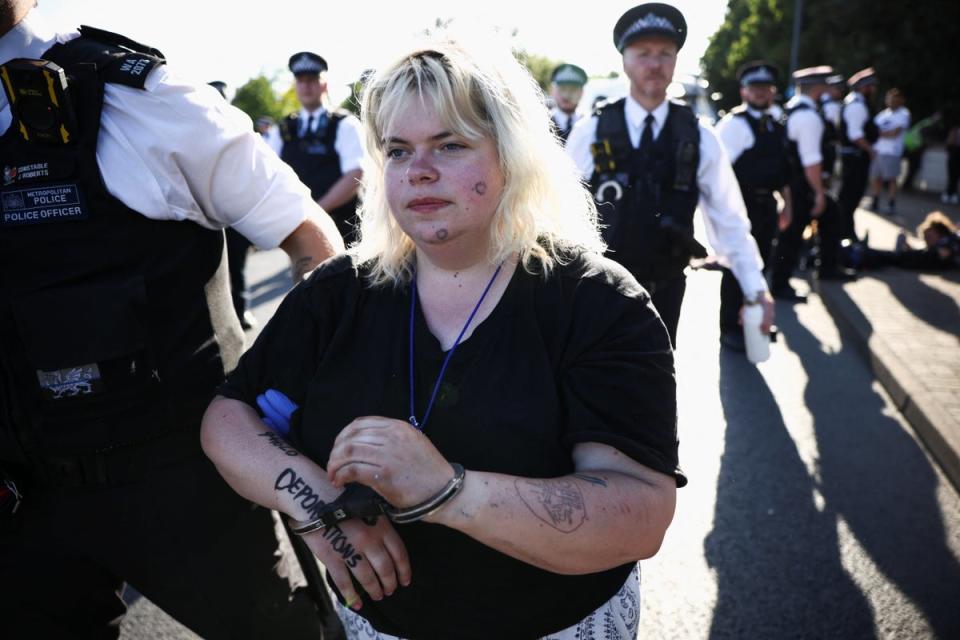 An activist blocking a road leading away from the Colnbrook Immigration Removal Centre is detained by police (REUTERS)