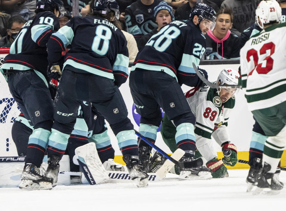 Minnesota Wild forward Frederick Gaudreau, second from right, attempts to get to the puck against Seattle Kraken forward Matty Beniers, far left, defenseman Cale Fleury, second from left, and defenseman Carson Soucy (28) during the second period of an NHL hockey game Friday, Nov. 11, 2022, in Seattle. (AP Photo/Stephen Brashear)