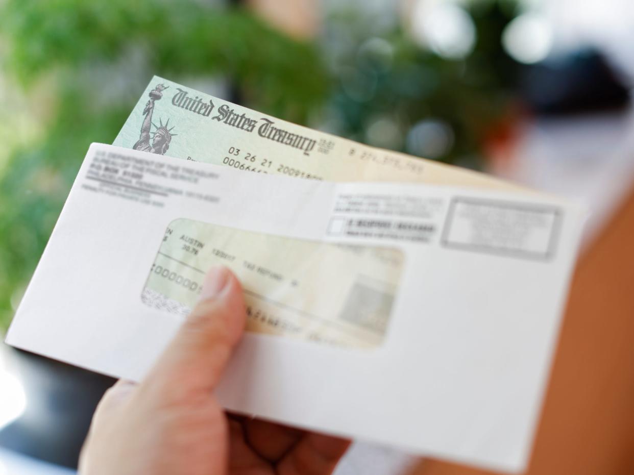 Man receives a tax refund check from the government; Indoor background