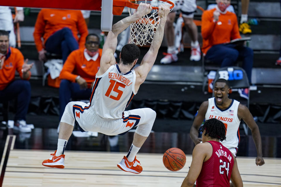 Illinois guard Da'Monte Williams, right rear, celebrates as Giorgi Bezhanishvili follows through on a dunk over Rutgers' Ron Harper Jr. during the second half of an NCAA college basketball game at the Big Ten Conference men's tournament in Indianapolis, Friday, March 12, 2021. (AP Photo/Michael Conroy)