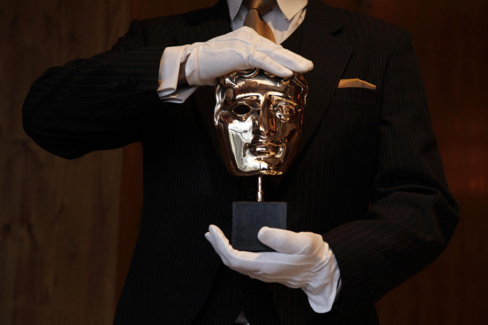 A British Academy of Film and Television Arts (BAFTA) award mask is displayed by an employee during a media viewing at the Savoy Hotel in London February 8, 2012. The BAFTA awards ceremony will take place on Sunday.   REUTERS/Stefan Wermuth (BRITAIN - Tags: ENTERTAINMENT SOCIETY)