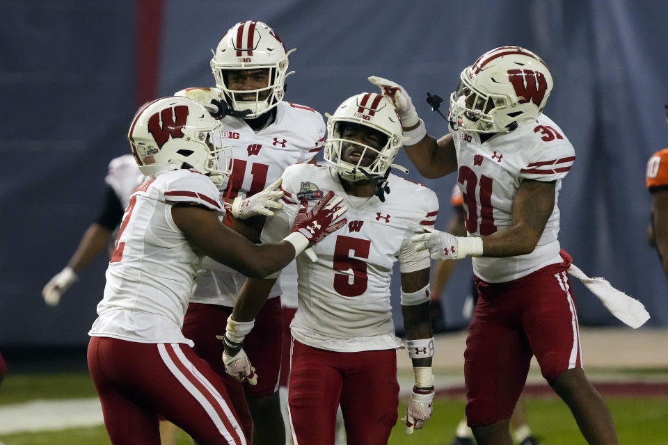 Wisconsin cornerback Cedrick Dort Jr. celebrates with Ricardo Hallman (2), Alexander Smith (11), and Amaun Williams (31) after intercepting the football against Oklahoma State during the second half of the Guaranteed Rate Bowl NCAA college football game Tuesday, Dec. 27, 2022, in Phoenix. Wisconsin 24-17. (AP Photo/Rick Scuteri)
