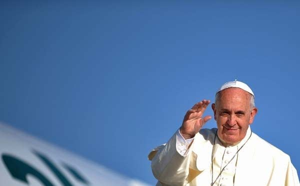 Pope Francis waves before entering his plane as he leaves Rome for Jordan.