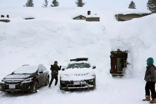 PHOTO: A person removes snow in front of lodging obscured by snowbanks piled up from new and past storms in the Sierra Nevada mountains, March 29, 2023, in Mammoth Lakes, Calif. (Mario Tama/Getty Images)