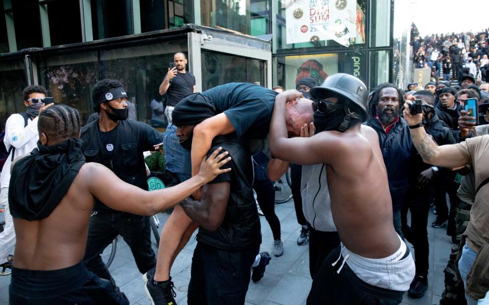 A group of men carry an injured man away after he was allegedly attacked by some of the crowd of protesters on the Southbank near Waterloo station on June 13 - Getty Images Europe