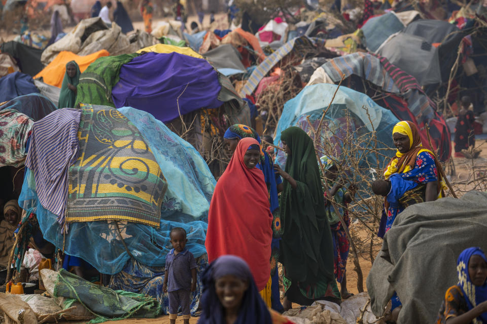 People walk through a displacement camp outskirts of Dollow, Somalia, on Monday, Sept. 19, 2022. Somalia is in the midst of the worst drought anyone there can remember. A rare famine declaration could be made within weeks. Climate change and fallout from the war in Ukraine are in part to blame. (AP Photo/Jerome Delay)