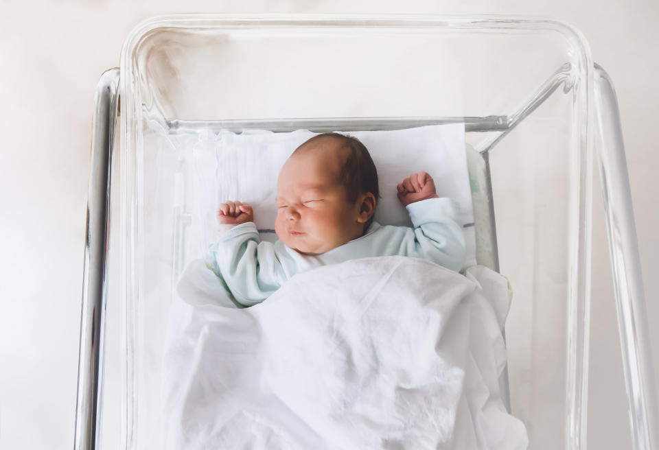 A newborn baby in a bed.