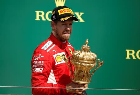 Formula One F1 - British Grand Prix - Silverstone Circuit, Silverstone, Britain - July 8, 2018 Ferrari's Sebastian Vettel celebrates winning the race on the podium with the trophy REUTERS/Andrew Yates