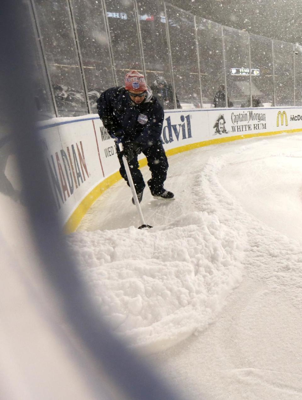 A members of the ice crew removes accumulative snow from the ice during the first period of an NHL Stadium Series hockey game between the Chicago Blackhawks and the Pittsburgh Penguins at Soldier Field on Saturday, March 1, 2014, in Chicago. (AP Photo/Charles Rex Arbogast)