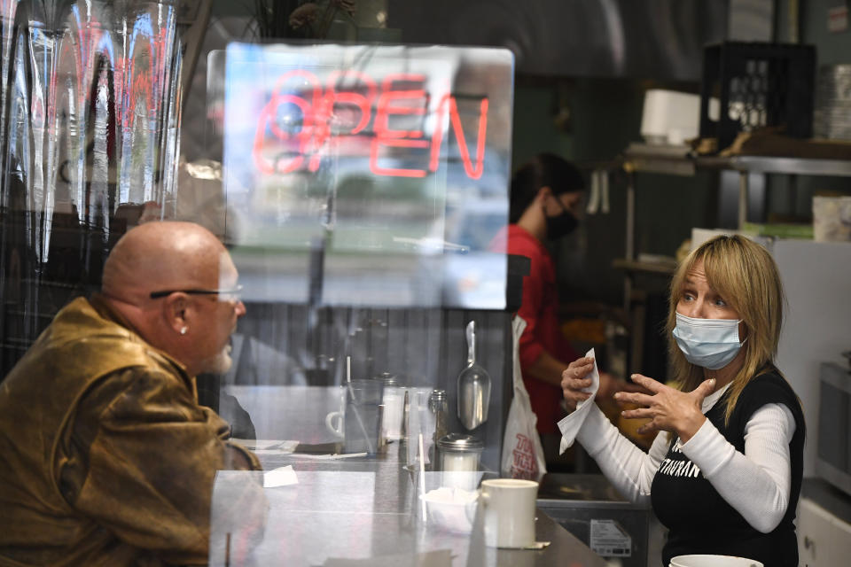 FILE - In this Thursday, Dec. 10, 2020, file photo, head waitstaff Laurie Mitchell, right, talks with a customer at Rodd's Restaurant, in Bristol, Conn, amid the coronavirus pandemic. Responses to the coronavirus pandemic and police brutality dominated legislative sessions in 2020 and led to many new laws that will take effect in the new year. (AP Photo/Jessica Hill, File)