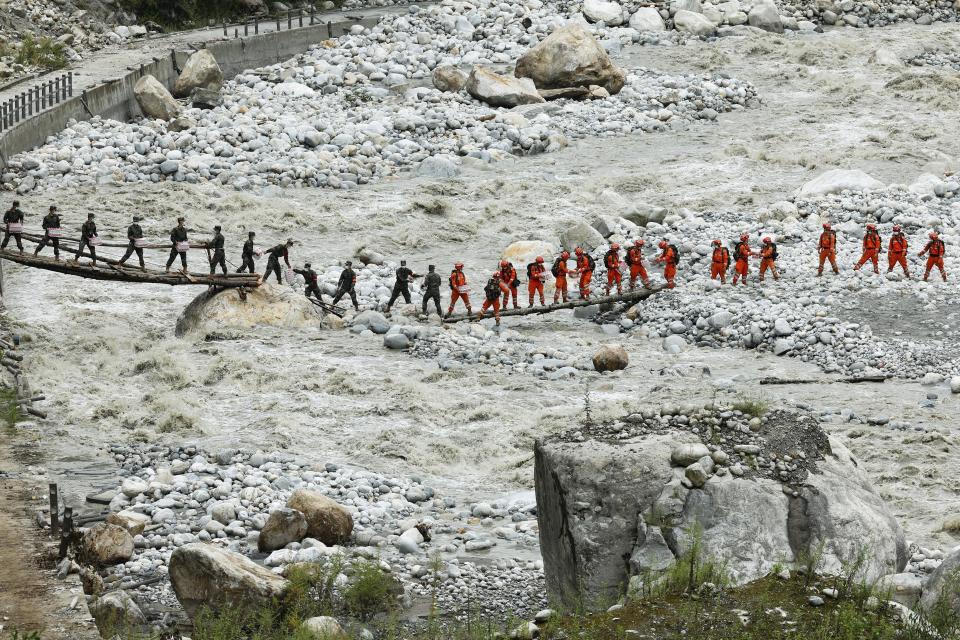 In this photo released by Xinhua News Agency, rescuers deliver supplies via a temporary bridge in the aftermath of an earthquake near Moxi Town of Luding County, southwest China's Sichuan Province, Sept. 8, 2022. Heavy rains are complicating earthquake recovery efforts in southwestern China, where the death toll from Monday's disaster has risen. (Shen Bohan/Xinhua via AP)