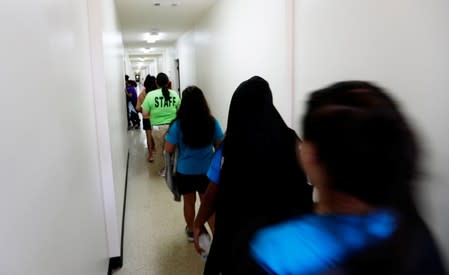 Immigrants walk down the hall of a dormitory at the U.S. government's newest holding center for migrant children in Carrizo Springs