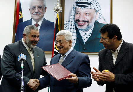 FILE PHOTO: Palestinian President Mahmoud Abbas (C) gives the letter of appointment to Prime Minister Ismail Haniyeh (L) as senior Fatah leader Mohammed Dahlan watches in Gaza February 15, 2007. REUTERS/Suhaib Salem/File Photo