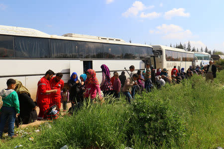 People who were evacuated from the two villages of Kefraya and al-Foua walk near buses, after a stall in an agreement between rebels and Syria's army, at insurgent-held al-Rashideen, Aleppo province, Syria April 15, 2017. REUTERS/Ammar Abdullah