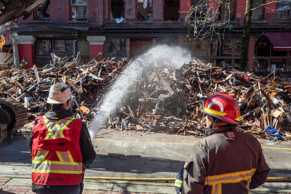Workers hose down debris and rubble from the demolition of the Winters Hotel on Vancouver's Abbott Street in Vancouver in April 2022.   (Ben Nelms/CBC - image credit)