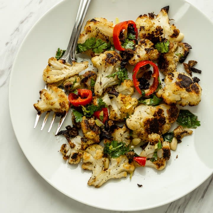 A plate of roasted cauliflower, herbs, and peppers