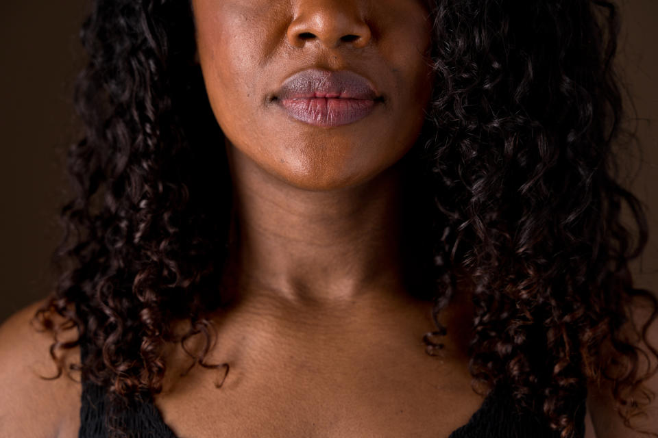 Close-up of a woman's face and shoulders with curly hair, wearing a sleeveless top