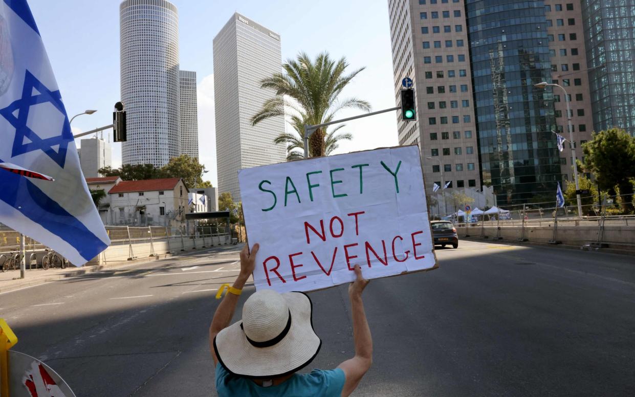 A woman sits on the middle isle of a road holding a placard demanding a 'prisoner deal', a week after Israeli hostages were snatched by the Palestinian militant group Hamas attack into southern Israel, outside the Ministry of Defense in Tel Aviv on October 16, 2023.