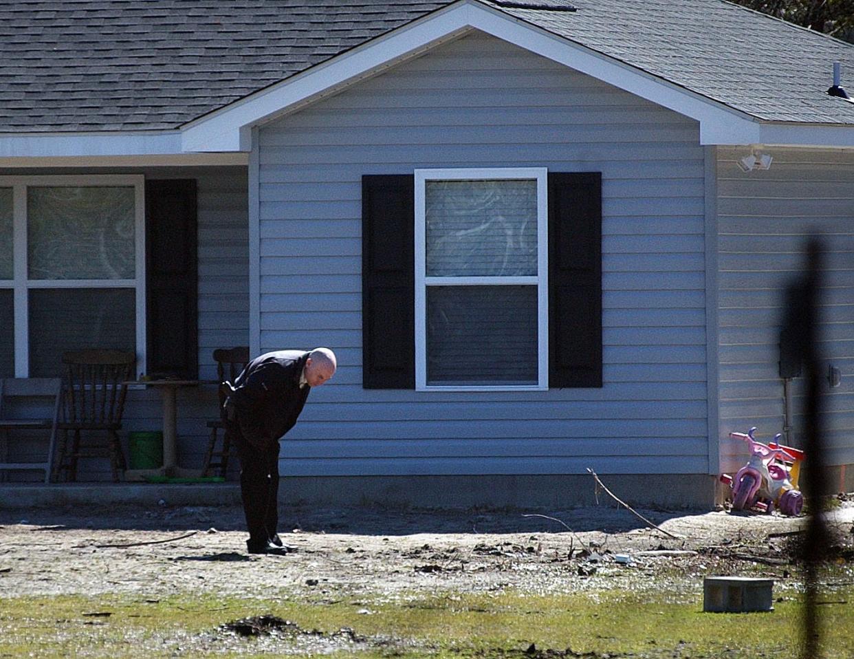 TERRY DICKSON/The Times-UnionA Glynn County police officer checks the yard of a Baumgardner Road home where, police said, a woman drowned her daughter, tried to drown her son and then shot herself to death.