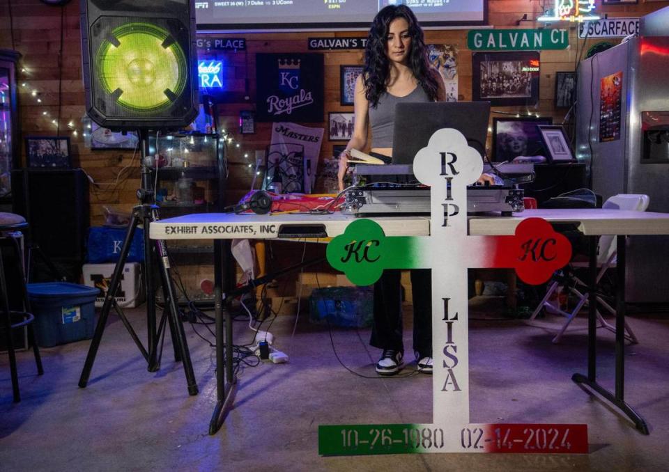 A sheet metal cross, in honor of Lisa Lopez-Galvan, stands propped against a table while Adriana Galvan, 19, practices at home with her late mother’s DJ equipment.
