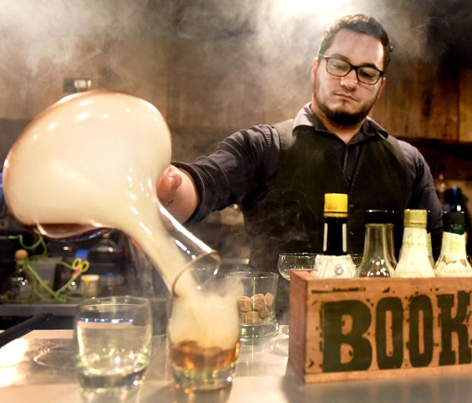 Steve Thomas-Peer, a bartender at Hops/Scotch 22 in Doylestown Borough, pours a custom-crafted, Smoke Old-Fashioned.