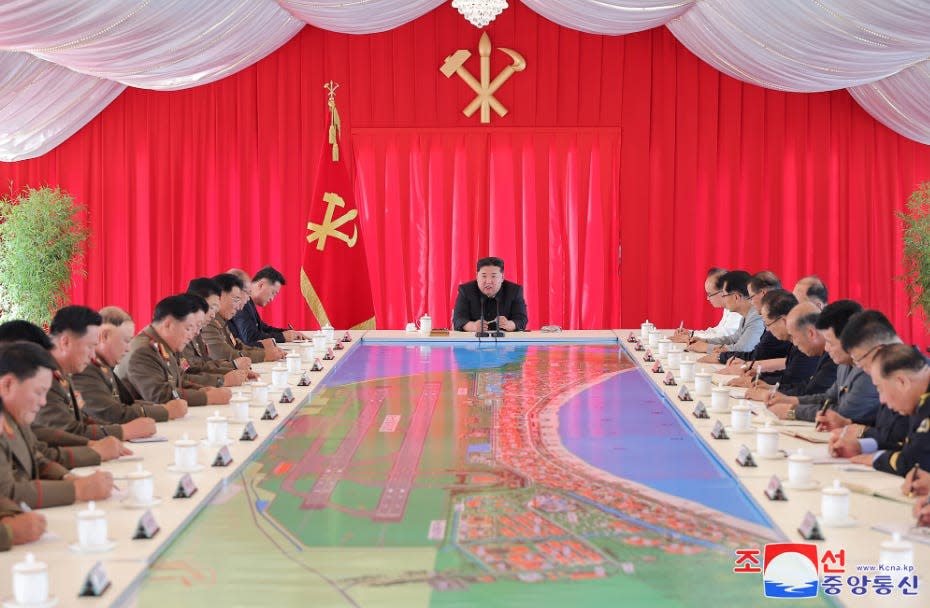 Kim Jong Un and deputies sat around a table.