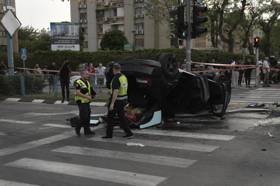 Israeli police investigate the overturned car carrying Israel's firebrand national security minister, Itamar Ben-Gvir, following an accident in Ramle, central Israel, Friday, April 26, 2024. Ben-Gvir was injured in a car accident and brought to the hospital Friday shortly after visiting the scene of a stabbing attack in central Israel, Israeli police say.(AP Photo/Mahmoud Illean)